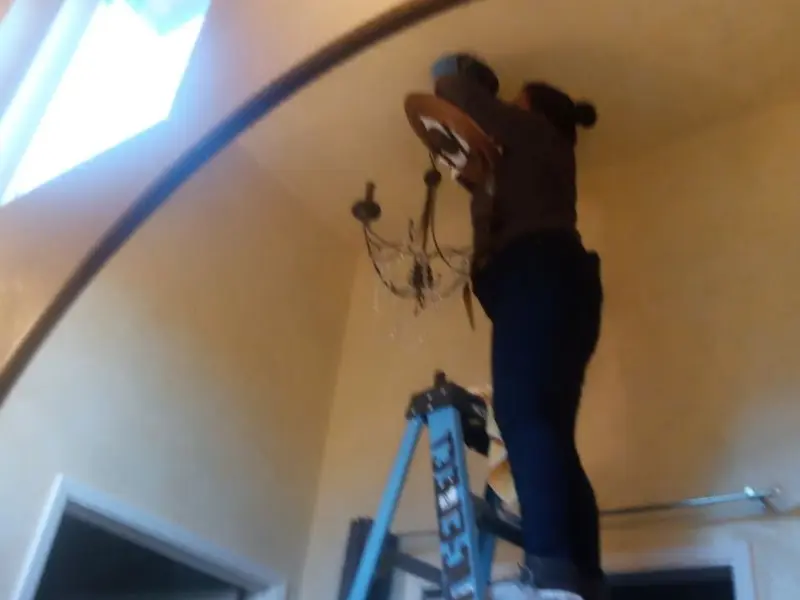 Electrician installing a chandelier in a Nahant residence